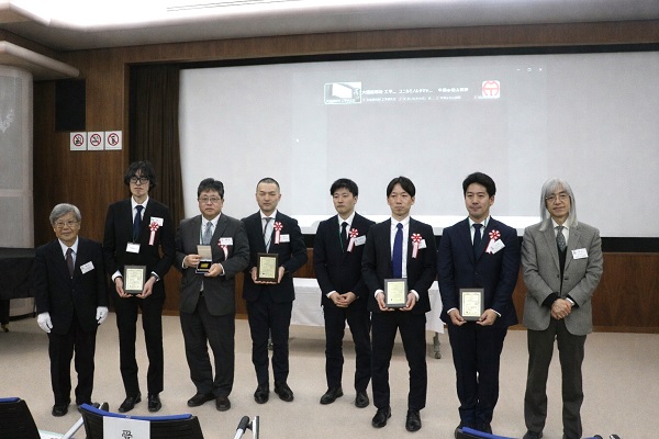 第18回岩木賞受賞者と関係者 左から、藤井氏、コニカミノルタジャパン・西本氏、コニカミノルタジャパン・若園敏美氏、日本食品化工・高口氏、日本食品化工・堀之内 歩氏、新東科学・北田暢也氏、ハイロックス・上代永氏、大森会長　mst 表面改質