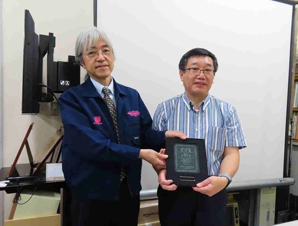 贈呈式のようす:大森委員長(左)と功労賞受賞の林氏(右)